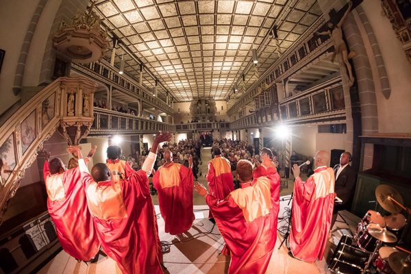 Das Ensemble in roten Roben singt in einer vollen Kirche